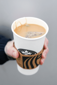 A hand holding a cup of Starbucks London fog tea latte.