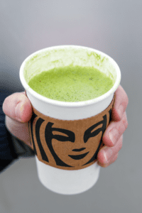 Hand holding a cup of Starbucks matcha latte.