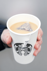 A hand holding a cup of Starbucks royal English breakfast tea latte.