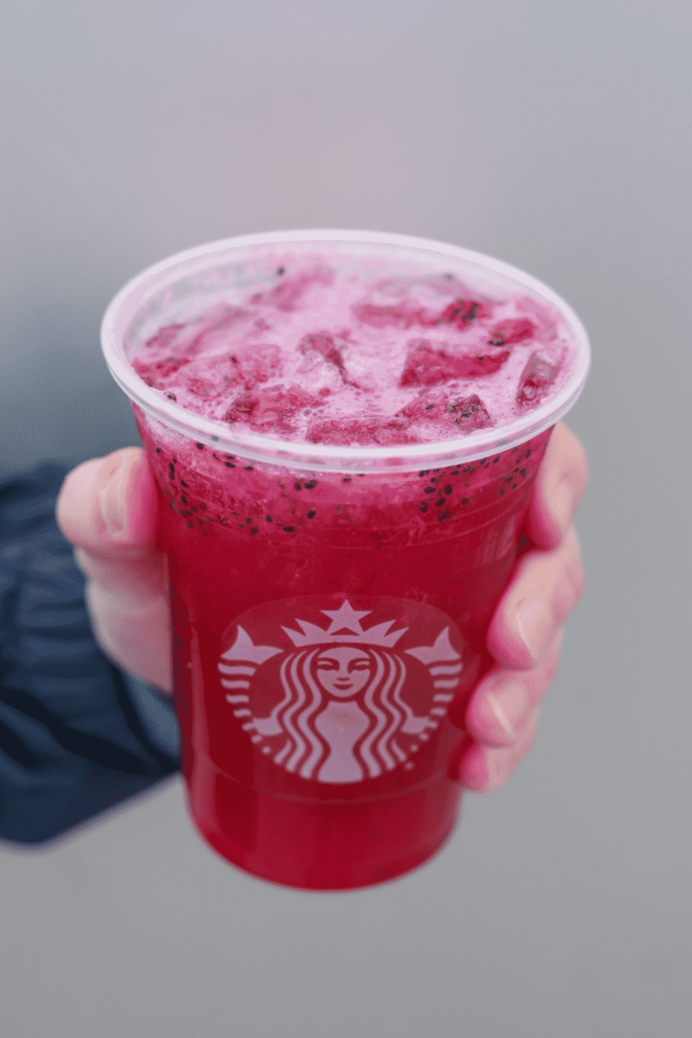 A hand holding a cup of Starbucks mango dragon fruit refresher.