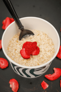 A cup of Starbucks oatmeal with a few freeze dried strawberries on top.