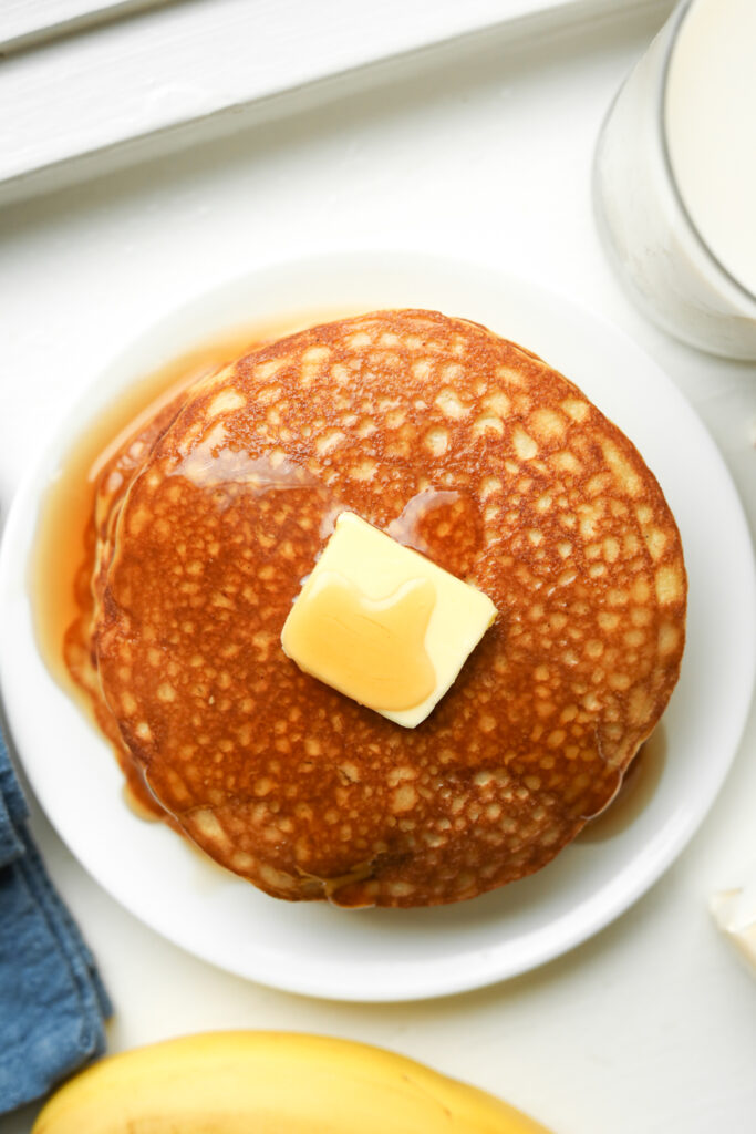 A stack of pancakes topped with butter and maple syrup.