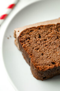 Chocolate cake topped with frosting on a white plate.
