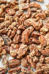 Candied pecans on a white sheet of parchment paper.
