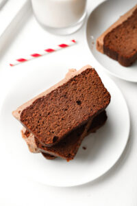 Three slices of chocolate yogurt cake stacked on top of one another on a white plate.
