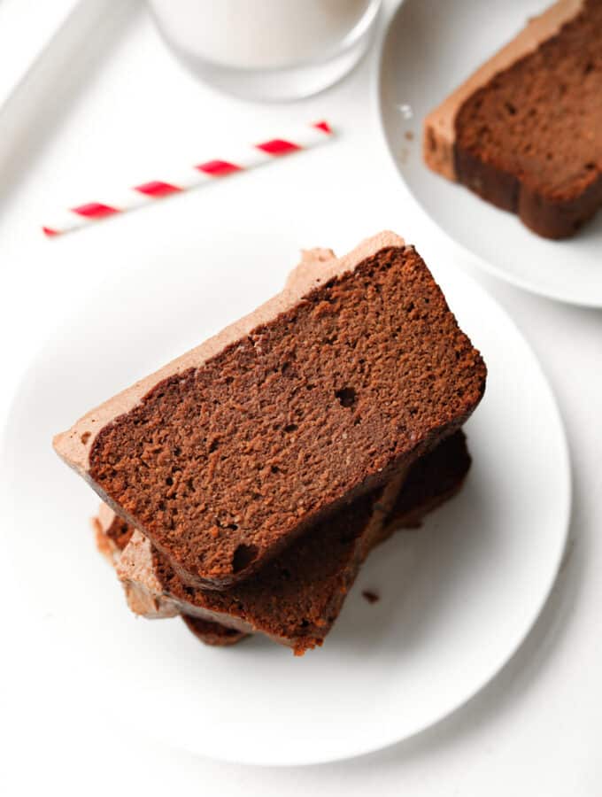 Three slices of chocolate yogurt cake stacked on top of one another on a white plate.