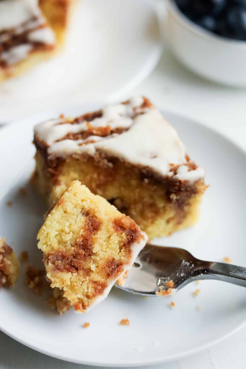 A fork holding a piece of coffee cake on a white plate.