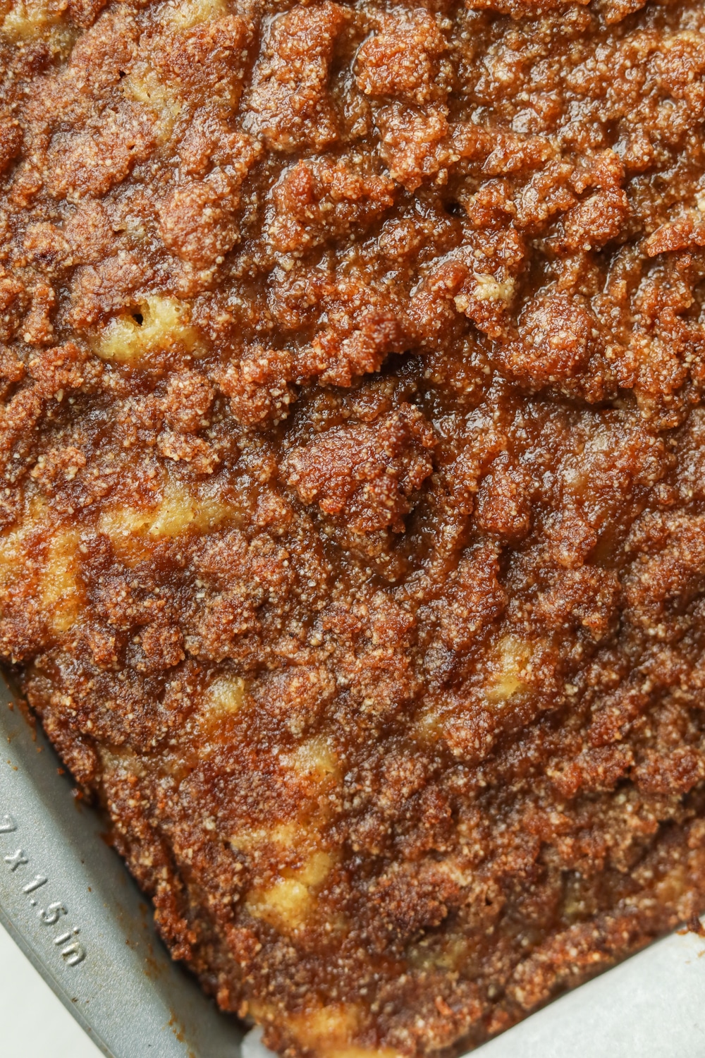 A cake tray filled with cake that has a cinnamon crumble topping on it.