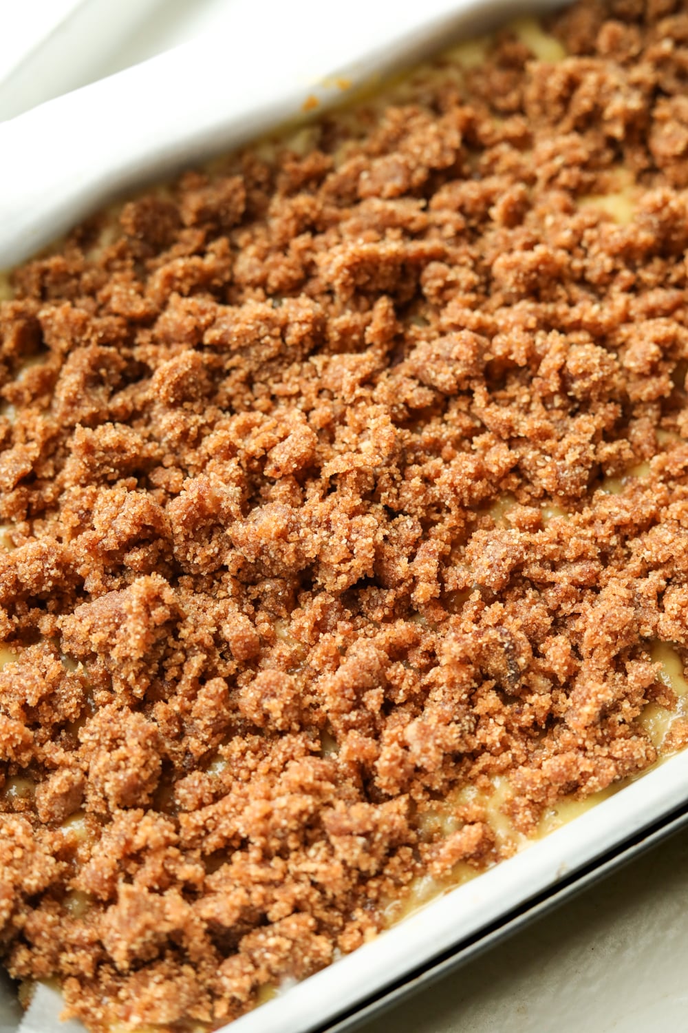 A cake tray filled with cake batter and a crumble topping.