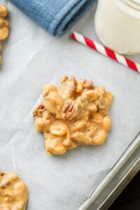 A peanut butter nut cluster on a baking sheet lined with white parts and paper and a red and white straw next to it.