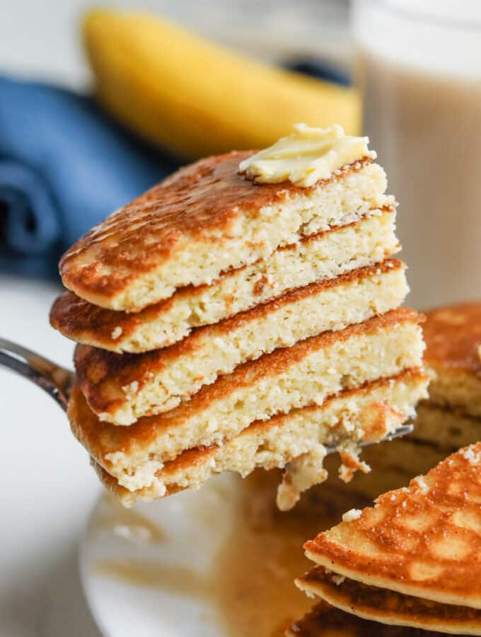 A fork pulling out a bunch cut up pancakes from a stack of them.