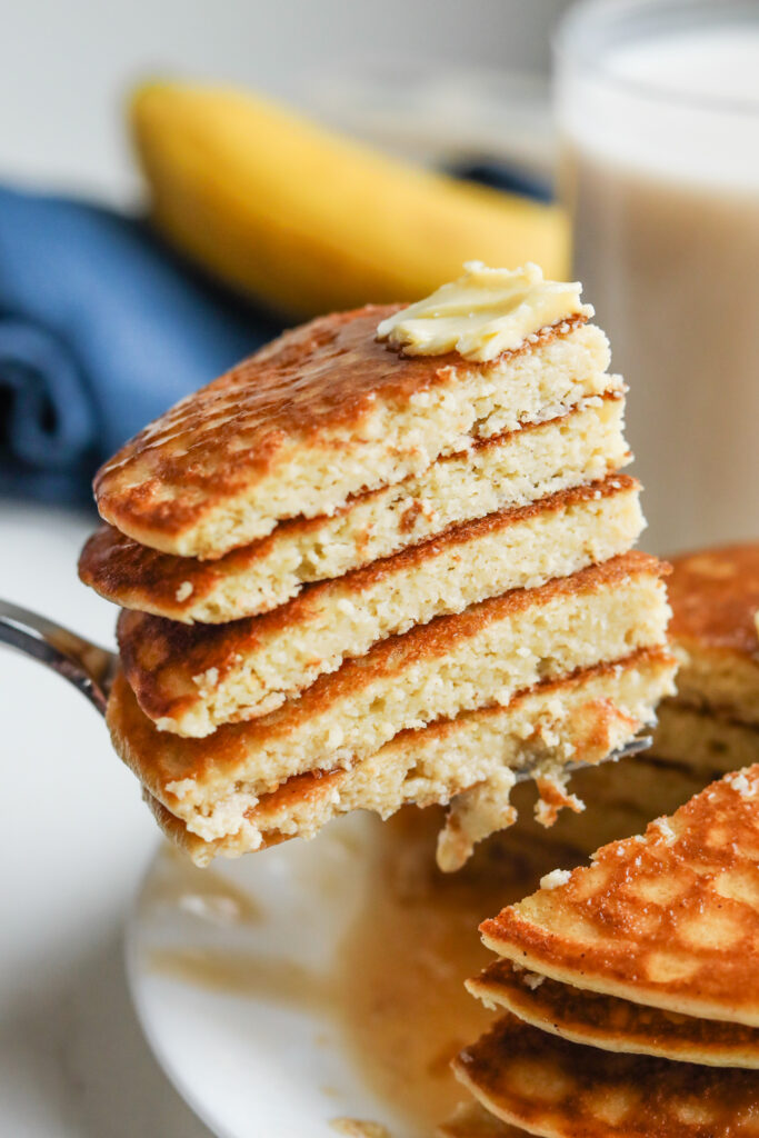 A fork pulling out a bunch cut up pancakes from a stack of them.