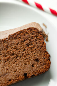 A slice of chocolate cake with chocolate frosting on a white plate.