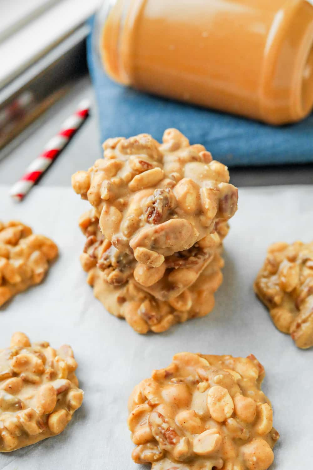 Three peanut butter nut clusters stacked on top of one another on a baking sheet lined with parchment paper.