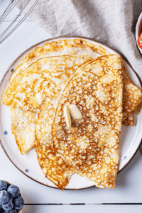 A white plate with a few crepes overlapping one another on it.