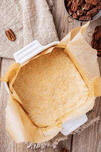 A baking dish with a pie crust in it on top of parchment paper.