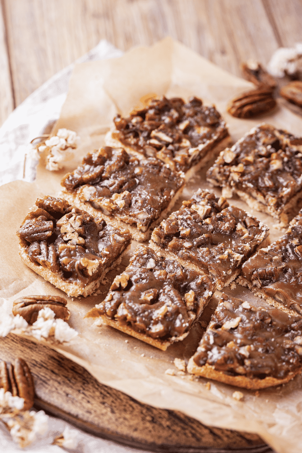 Seven pecan pie bars on a piece of parchment paper on a wooden cutting board.