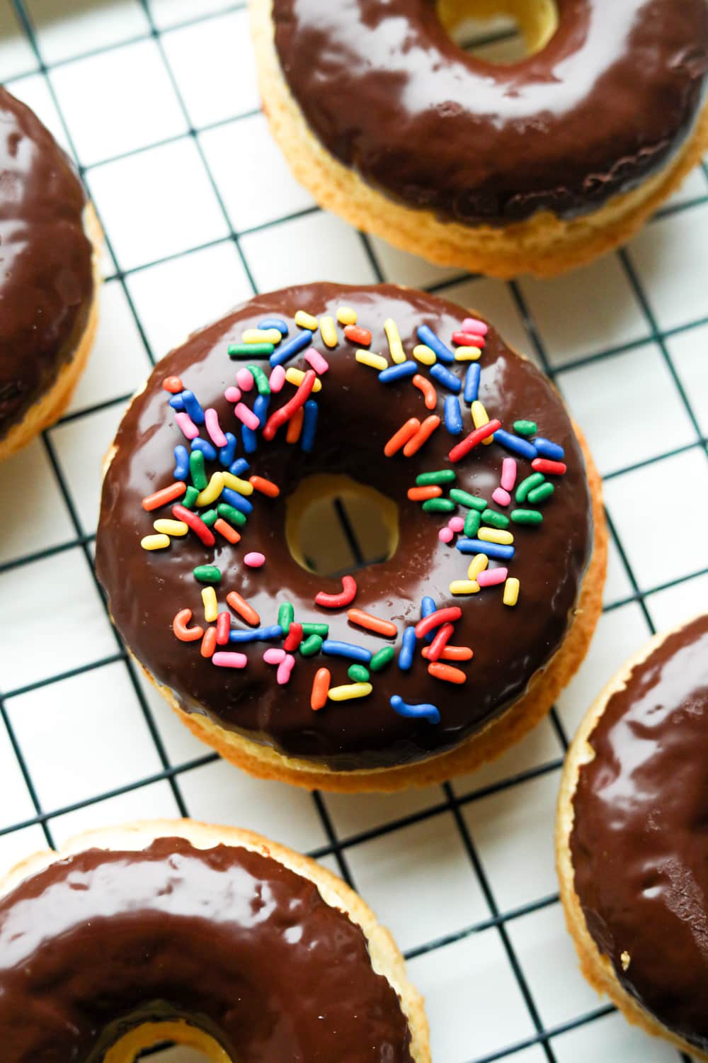 I donut top with sprinkles on a drying rack.