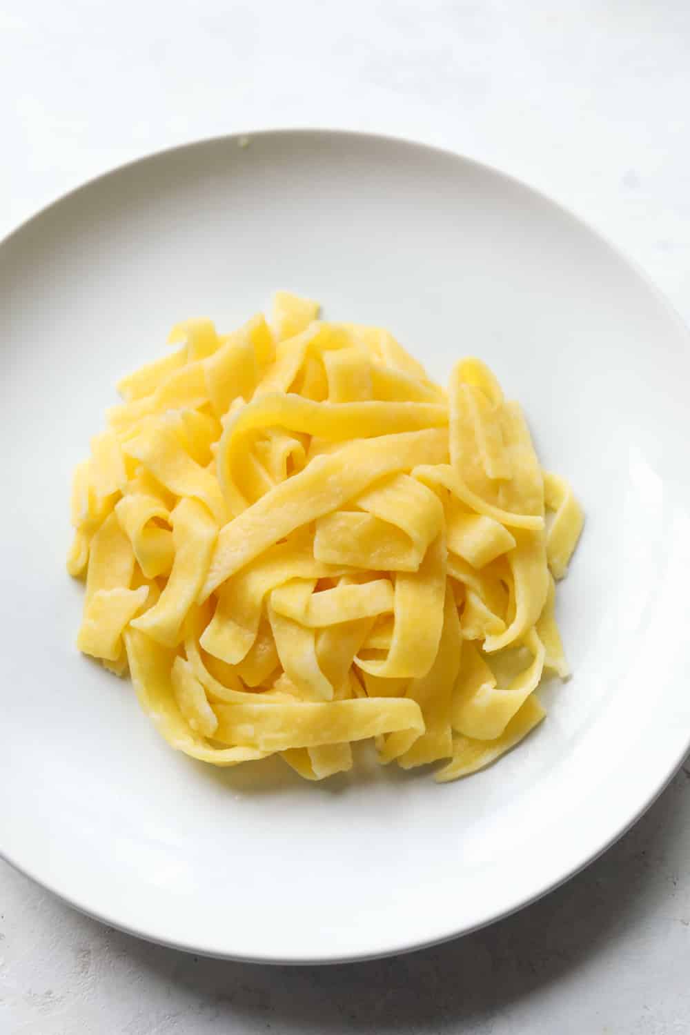 Linguini noodles on a white plate.