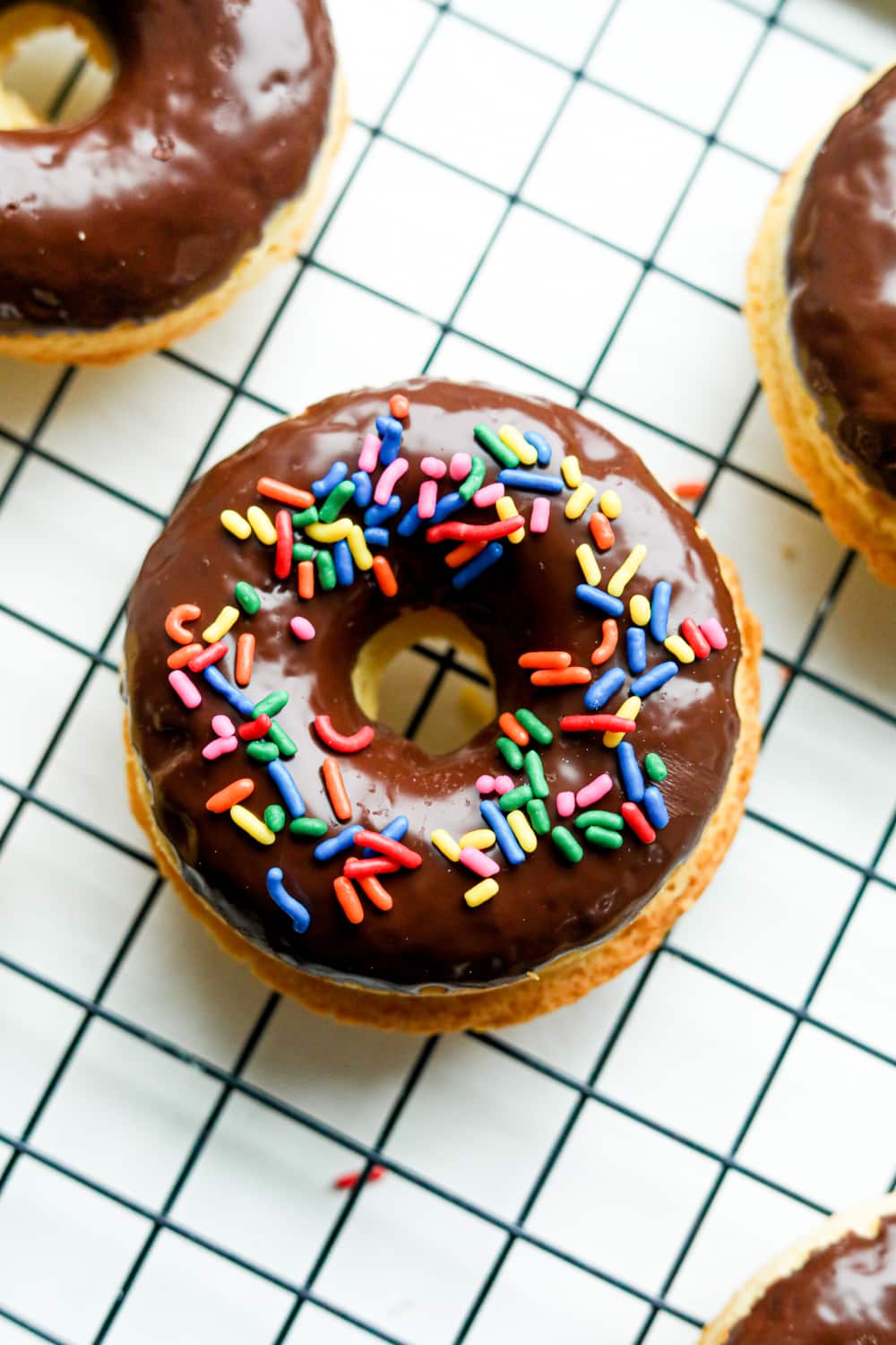 A donut on a black wire rack. There are other donuts around it.