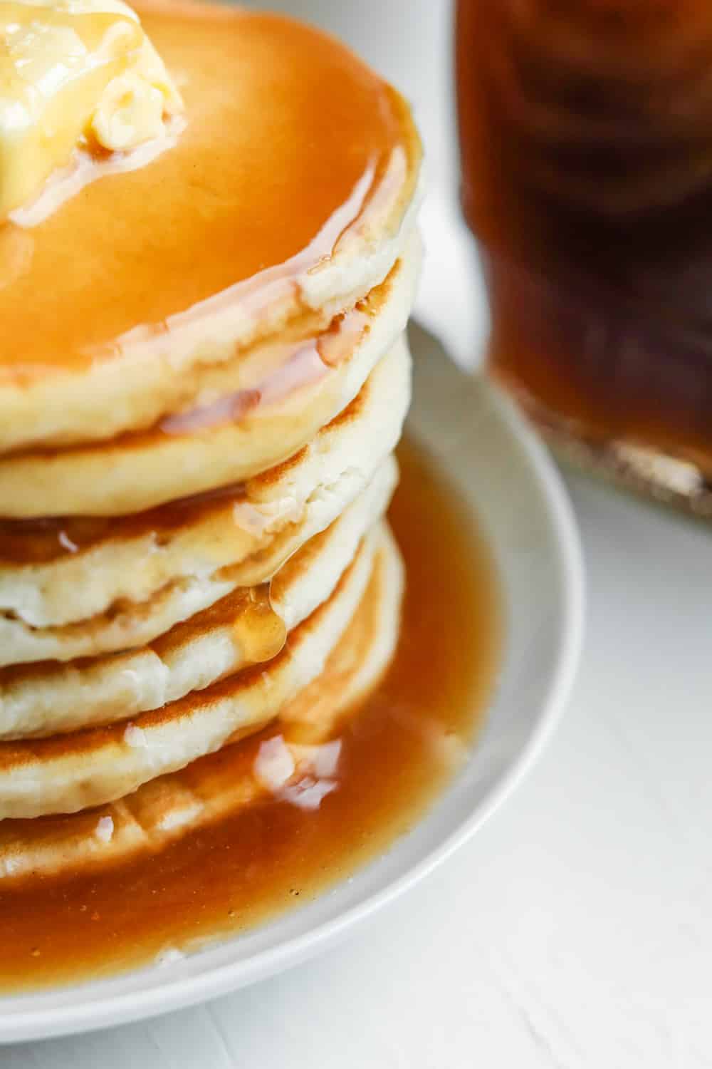 A stack of pancakes with maple syrup dripping down the side of them.