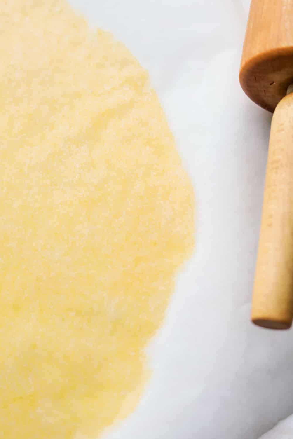 Pasta dough that's been rolled out between two sheets of parchment paper.