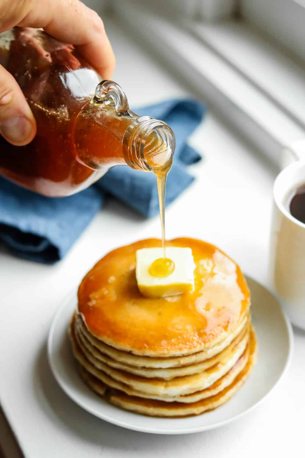 Maple syrup being poured on pancakes.