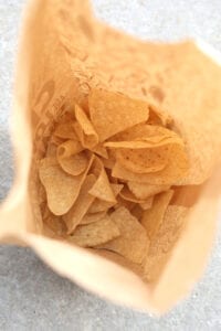 A brown bag filled with tortilla chips.