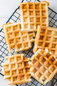 Five keto waffles on a black wire rack.