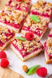 A few raspberry cheesecake bar squares on a piece of parchment paper.