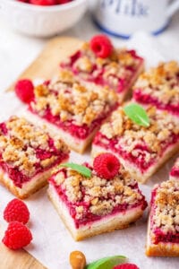 Two rows of three raspberry cheesecake bars on a piece of parchment paper.