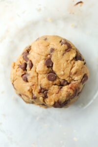 A ball of cookie dough in a clear bowl.