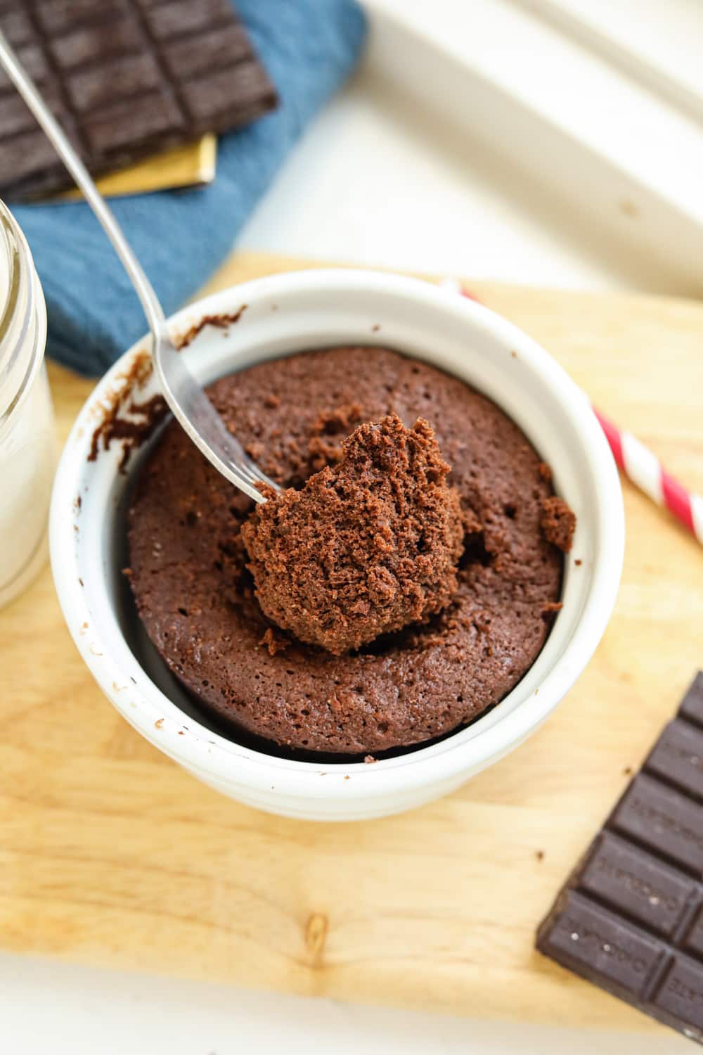 A fork holding a piece of chocolate cake in a white mug.