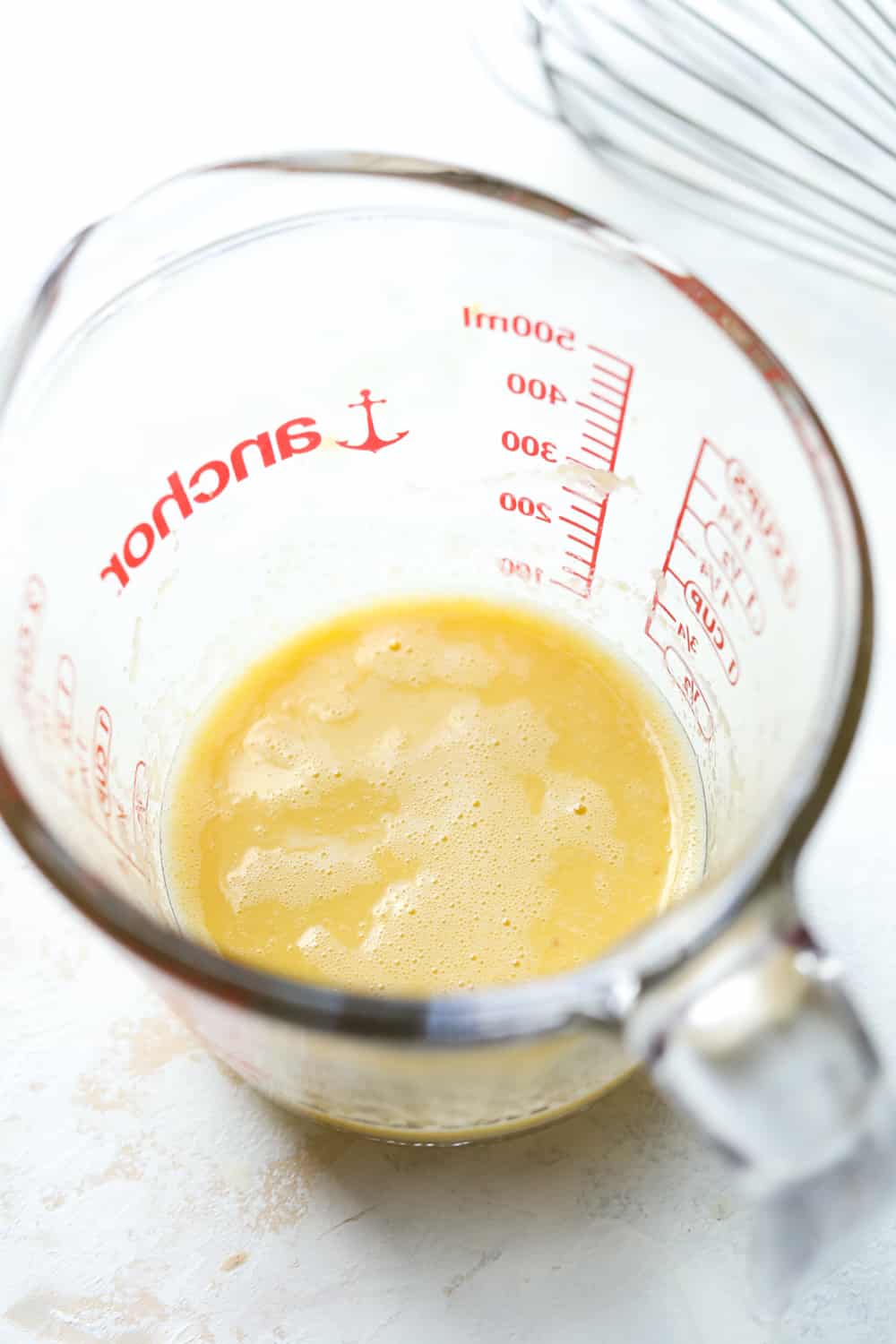 An egg and applesauce whisked together in a small measuring cup.