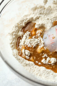 A clear bowl filled with flour and a brown butter mixture.