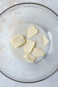 A clear bowl filled with cubed butter and almond milk.