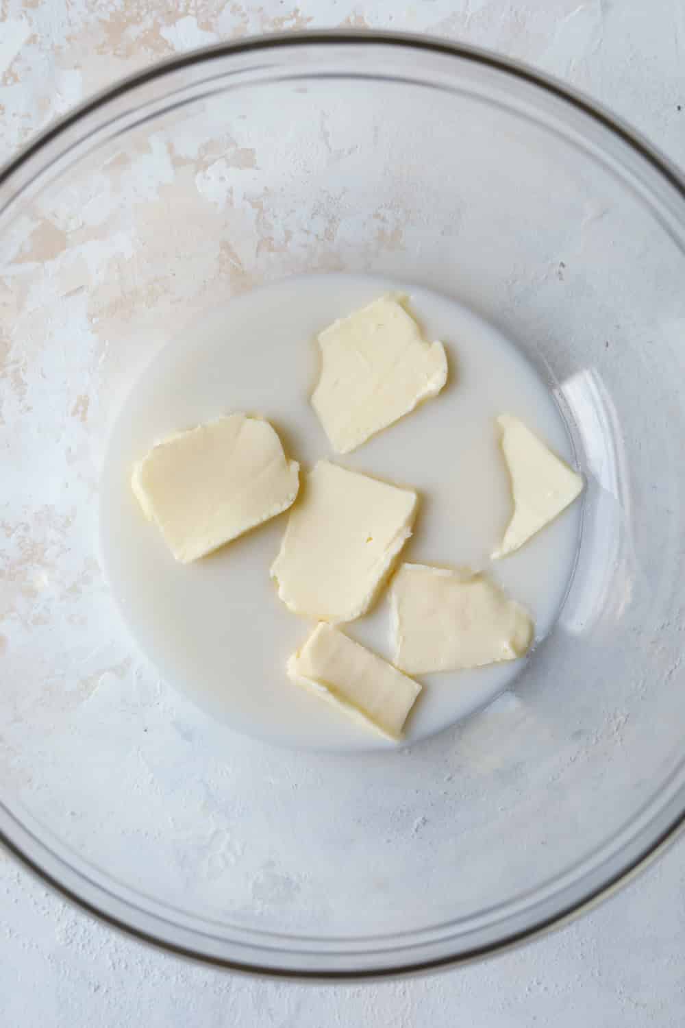A clear bowl filled with cubed butter and almond milk.