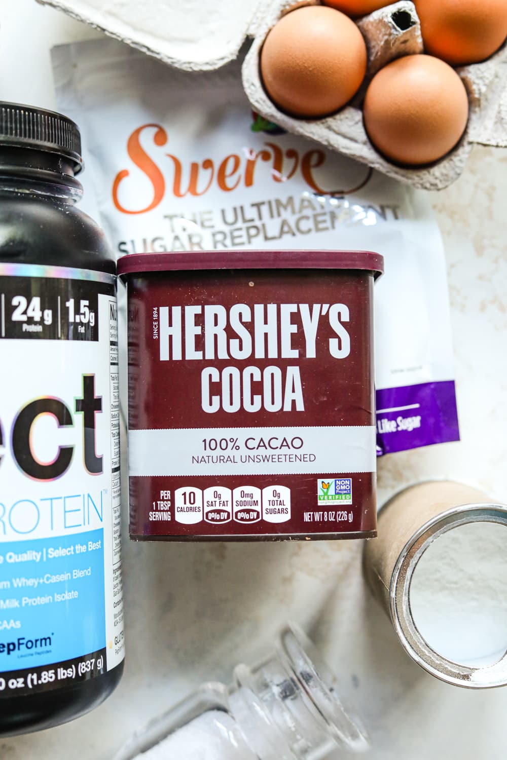 Ingredients used to make a chocolate mug cake on a white backdrop.