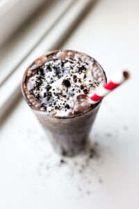 A chocolate smoothie inside of a glass topped with whipped cream.