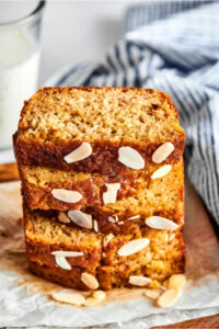 Five slices of banana bread stacked on top of one another and a piece of white parchment paper.