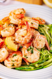 A white bowl with zoodles and shrimp scampi in it.