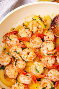 Part of a skillet with shrimp scampi in it.