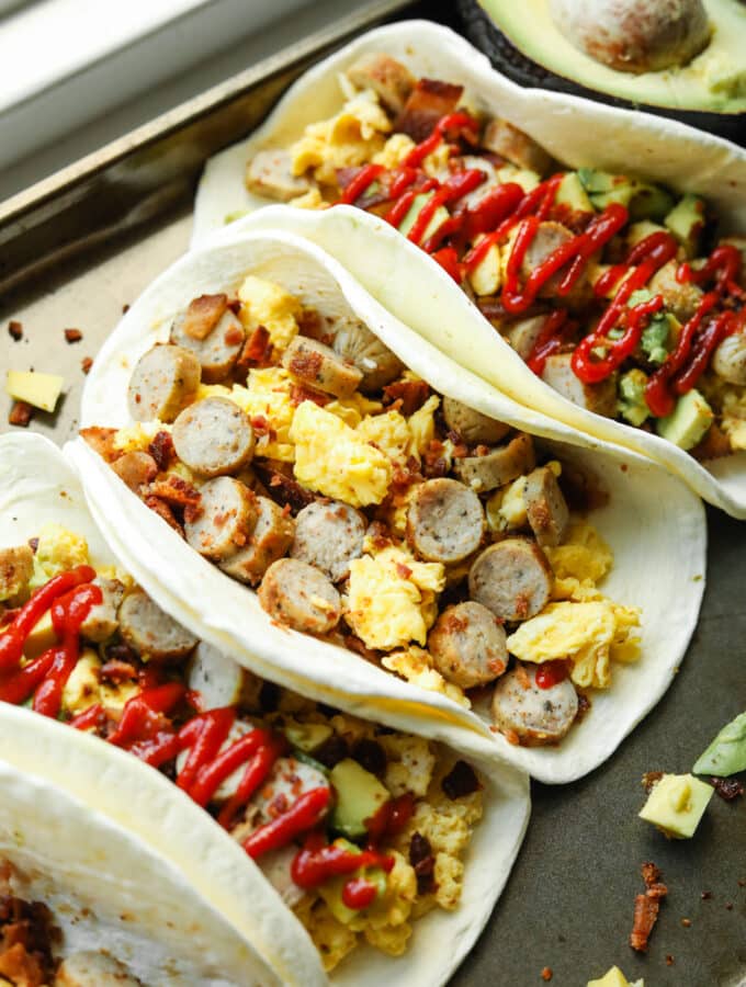 Several breakfast burritos on a gray baking tray.