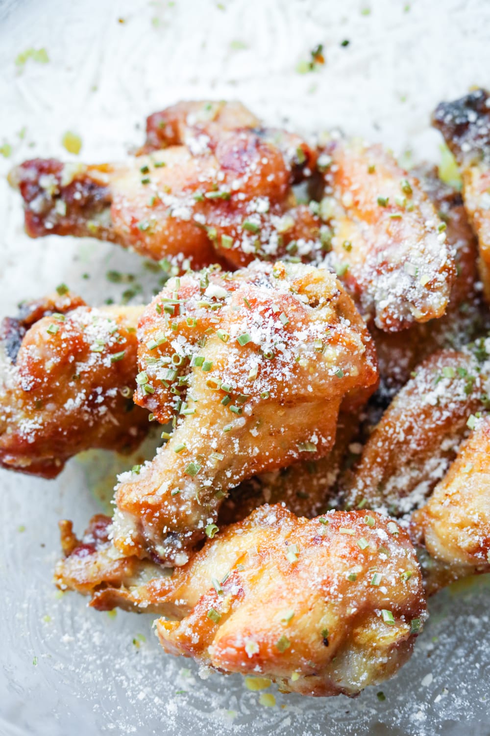 Garlic parmesan chicken wings being sauced in a bowl.