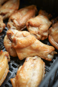 Chicken wings in an air fryer after one interval of cooking.