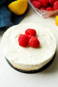 Cheesecake topped with raspberries set on the bottom of a black pan.