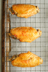 Cooked chicken wings on a wire rack.