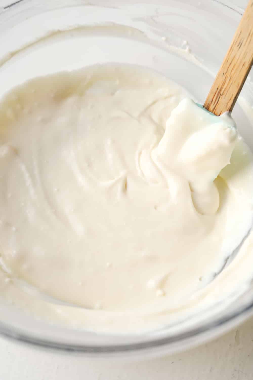 Cheesecake filling in a glass bowl. There's a spatula in the bowl.