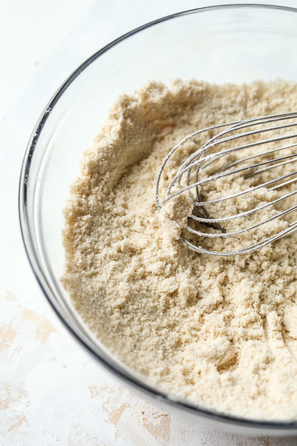 A bowl filled with dry ingredients and a wire whisk.