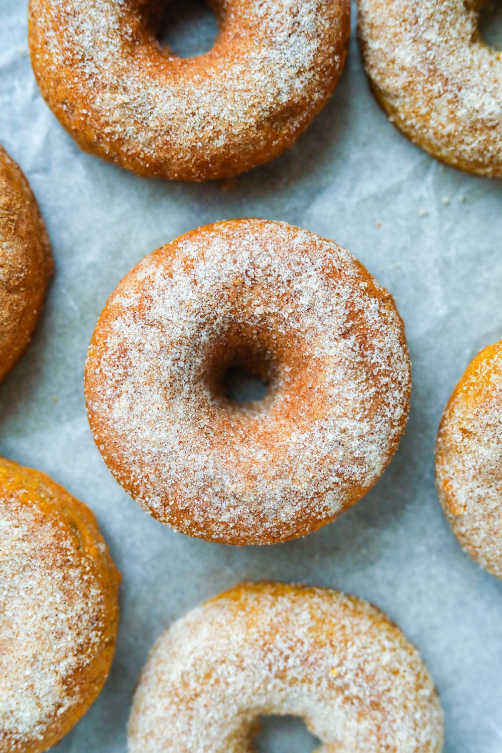 Pumpkin spice donuts on a white sheet of parchment paper.